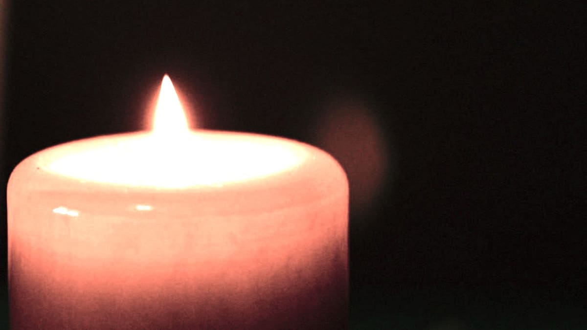 Flamme de bougie droite dans une pièce plongée dans la pénombre