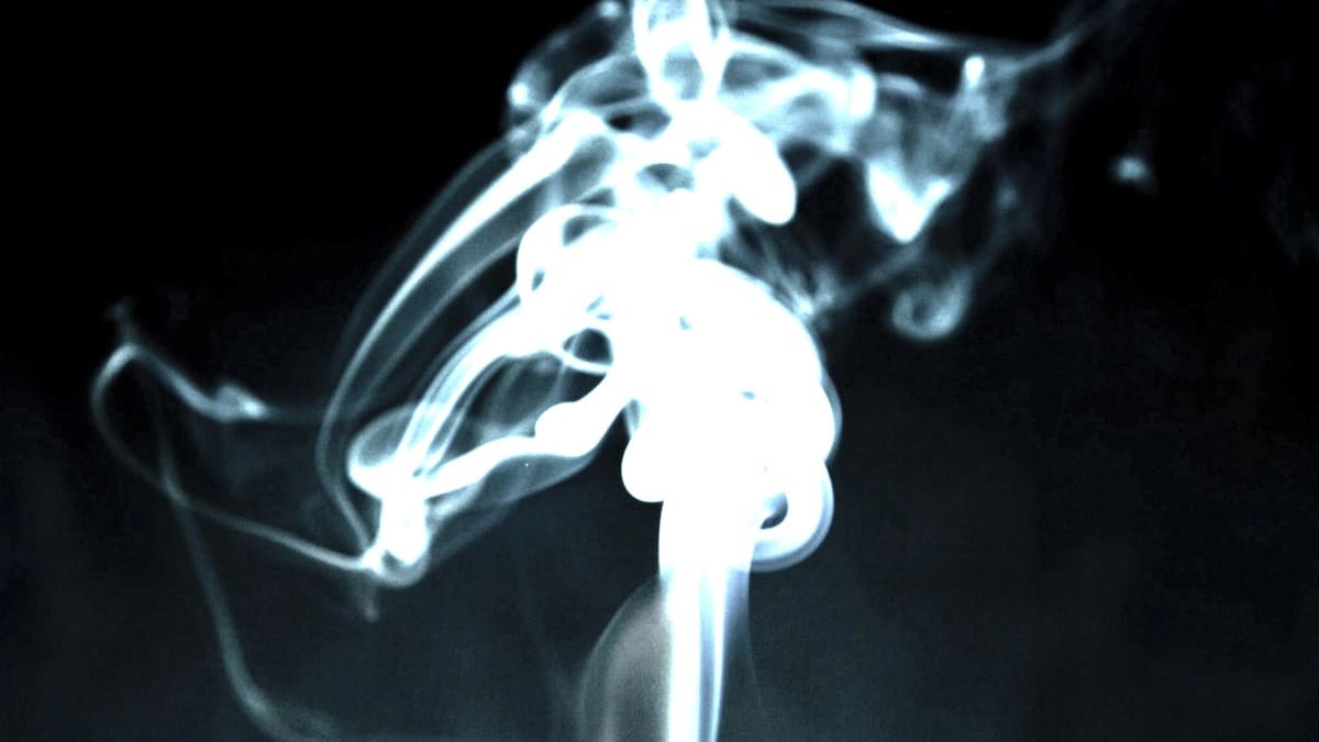 Fumée d'encens montant en volutes dans le noir